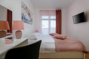 een slaapkamer met een bed en een bureau met een televisie bij Villa Dora in Pula