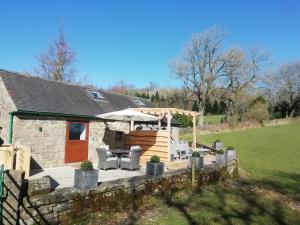 a house with a deck with an umbrella and chairs at Sabine Hay Barn in Matlock