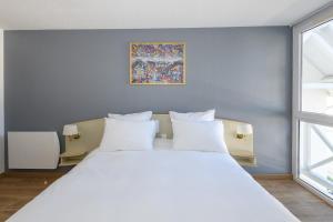 a bedroom with a large bed with white pillows at Grand Hôtel d'Espagne in Lourdes