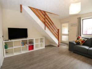 a living room with a couch and a tv at Wren Cottage in Weymouth