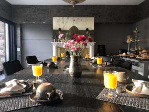 una mesa de comedor con un jarrón de flores y zumo de naranja en Villa Pura Vida en Kortrijk