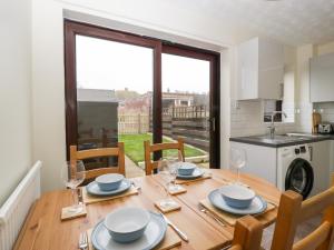 a kitchen and dining room with a wooden table and chairs at Wren Cottage in Weymouth