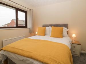 a bedroom with a bed with yellow sheets and a window at Wren Cottage in Weymouth