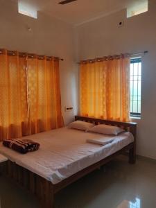 1 dormitorio con 1 cama grande y cortinas de color naranja en Aikya homestay, en Gokarna