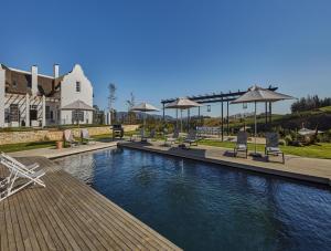 a pool with chairs and umbrellas next to a house at Brookdale Estate - Manor House in Paarl