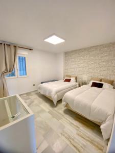 Duas camas num quarto branco com uma janela em Puerto Banus Duplex Centric WaterFront 3 Bedroom em Marbella