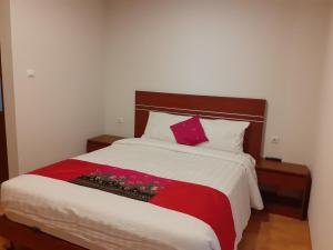 a bedroom with a large bed with a red and white blanket at Griya Bun Sari in Sukawati