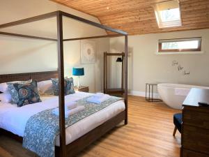 Pheasant Lodge with Hot Tub في Forgandenny: غرفة نوم بسرير وحوض استحمام ومغسلة
