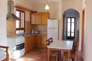a kitchen with a table and a white refrigerator at Hanakia in Stoupa