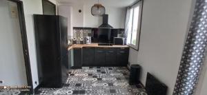 a kitchen with a black refrigerator and a tile floor at Superbe appartement tout équipé proche Hypercentre in Bergerac