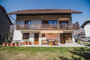 a house with a balcony and a table and chairs at Apartma Rombon Brdo with Free Onsite Parking in Bovec