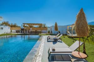 a swimming pool with lounge chairs and a villa at Sonel Luxury Villa, a Family Retreat, By ThinkVilla in Mouzákion