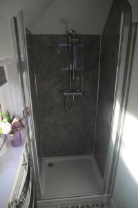 a shower with a glass door in a bathroom at The Wee Bank House in Oban