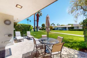 a patio with a glass table with chairs and an umbrella at Palm Springs Condo, Sunrise Villas in Palm Springs