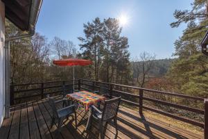a table and chairs on a deck with an umbrella at Ferienhaus Waldblick in Funfseen