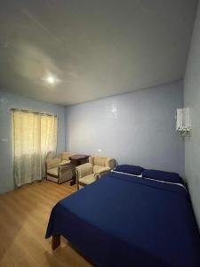 a bedroom with a blue bed and two chairs at C - Side Inn in Mambajao