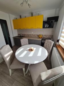 una mesa blanca y sillas en una cocina con armarios amarillos en Stephanie Apartment, en Galaţi