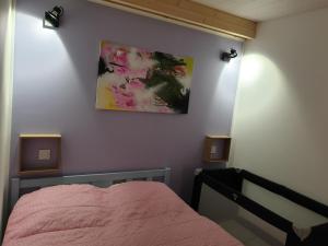 a bedroom with a pink bed and two lights on the wall at Le Chalet des Roses in Veules-les-Roses