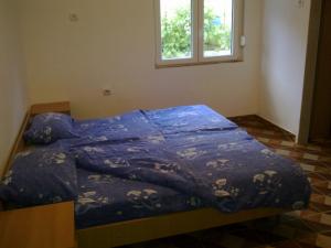 a bed with a blue comforter in a room with a window at Guest House Sandra in Kotor