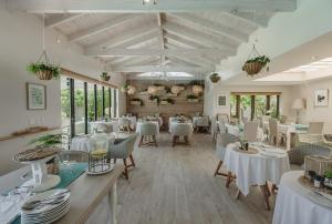a dining room with white tables and chairs at Cottage Pie by Robberg in Plettenberg Bay