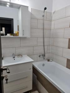 a bathroom with two sinks and a tub and a mirror at Stephanie Apartment in Galaţi