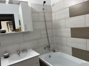 a bathroom with a white tub and a sink at Stephanie Apartment in Galaţi
