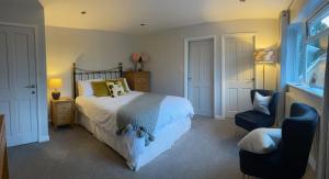 a bedroom with a bed and a chair and a window at Bricket House in Great Malvern