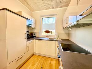 a large kitchen with white cabinets and a window at DarssAhoi in Pruchten