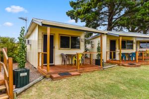 a small yellow house with a deck and chairs at Millicent Hillview Caravan Park in Millicent