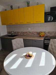a kitchen with a white table and yellow cabinets at Stephanie Apartment in Galaţi +6 photos