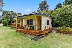 una pequeña casa blanca y amarilla con terraza en Millicent Hillview Caravan Park, en Millicent