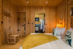 Fournet-BlancherocheにあるDomaine de l'Authentique Cabanes dans les arbresの木製の壁のベッドルーム1室、ベッド1台、椅子が備わります。