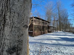 um velho edifício na neve ao lado de uma árvore em Rock Stalls Lodge Hocking Hills em Logan