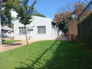 una casa blanca con un árbol en el patio en Triple9 Hatfield Guesthouse en Pretoria
