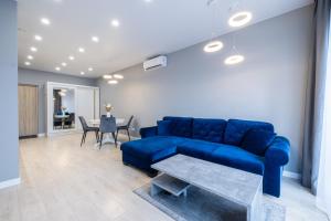 a living room with a blue couch and a table at HARMONY Stay APARTAMENTAI su terasa ir vaizdu į miestą in Telšiai