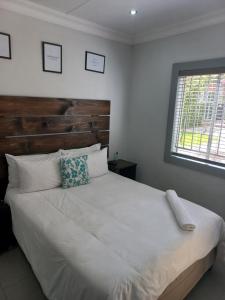 a bedroom with a large white bed with a wooden headboard at Triple9 Hatfield Guesthouse in Pretoria