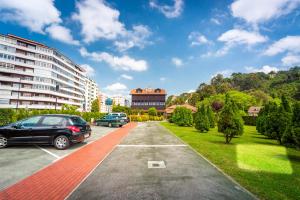 a parking lot with cars parked in front of a building at Hotel Castillo de Gauzón in Salinas