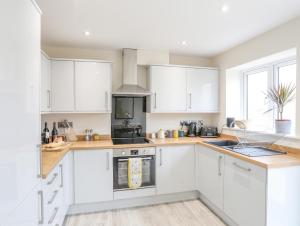 a kitchen with white cabinets and a stove at Swn Y Nant in Holyhead