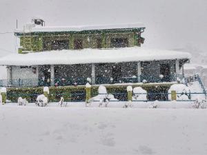un edificio cubierto de nieve en un patio en Chirping Orchard, Mukteshwar en Mukteswar