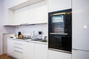 cocina con armarios blancos y microondas negro en Lighthouse Apartment, en Oporto
