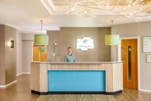 Una donna in piedi dietro una reception in un atrio dell'ospedale. di Holiday Inn Darlington - NORTH A1M, JCT.59, an IHG Hotel a Darlington