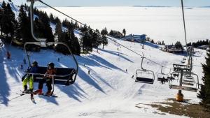 two people riding on a ski lift in the snow at Koča pri Binci in Cerklje na Gorenjskem