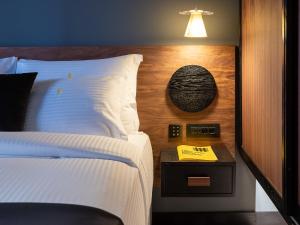 1 dormitorio con cama blanca y mesita de noche con lámpara en 3 Pines Design Living, en Heraclión