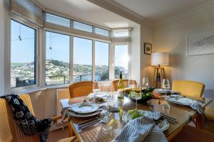 a dining room with a table and chairs and windows at Uphigh - Elevated Family Home with Stunning River Views in Dartmouth