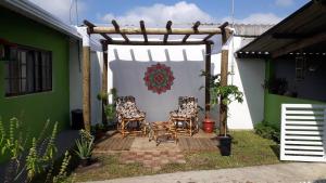 a pergola with two chairs sitting on a patio at Edícula - Casa de hospedes - em Cananeia SP com ar condicionado in Cananéia
