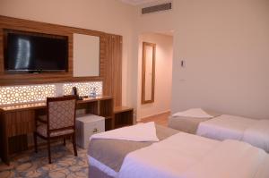 a hotel room with two beds and a desk with a television at Artal Al Alami Hotel in Al Madinah +24 photos