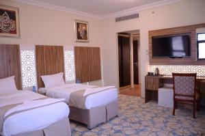 a hotel room with two beds and a desk and a television at Artal Al Alami Hotel in Al Madinah +30 photos