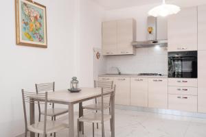 a kitchen with white cabinets and a wooden table and chairs at Rossi Tramonti 1, in Corniglia