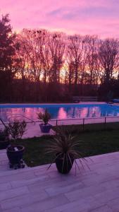 a swimming pool with a sunset in the background at Les loges in Parthenay