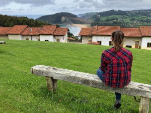 a woman sitting on a wooden bench in a field at Apartamentos Monterodiles in Liñero